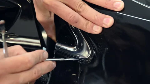 Closeup of a man's hands folding edges of vinyl film to cover chrome elements of Vídeos de archivo 139601858