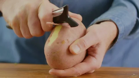 Closeup Of Man's Hands Peeling Potato Over Cutting Board Stock Footage 86069677