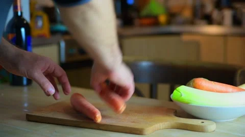 Closeup of a man's hands peeling vegetables on a wooden board. Footage FHD Stock Footage 147045098
