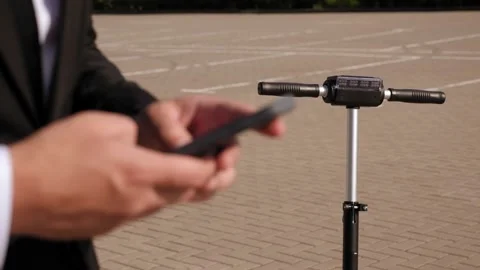 Closeup of man's hands with a phone, with an electric scooter in the background. Stock Footage 146301132