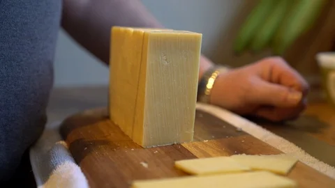 Closeup of man's hands slicing cheese with serrated knife on wooden board, 4k 스톡 동영상 86985739