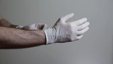 A closeup of a mans hands taking of latex gloves. 24FPS HD. Stock Footage 128499100