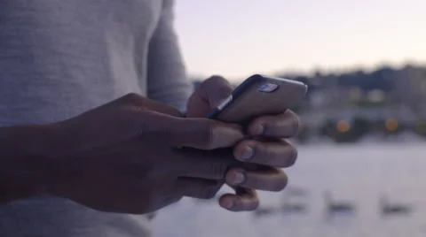 Closeup of Man's Hands Texting On Smartphone, River And Cityscape In Background Stock Footage 67942102