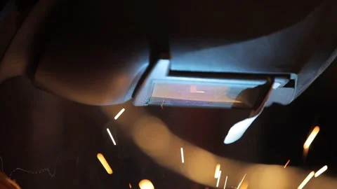 Closeup mask of welder, camera makes panorama down onto metal spray. Stock Footage 136429280