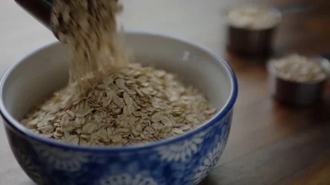Closeup Of Measuring Cup, Full Of Oats, Pouring Into Bowl, Slow Motion, 4K Video stock 82330096