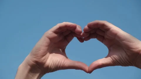 Closeup of men hands against blue sky in shape of heart. symbol of love. Stock Footage 232761995