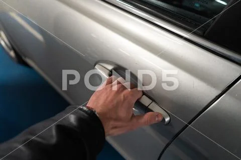 Closeup a men's hand on the latch of a car door opening it up - Light color car Stock Photos