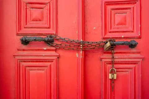 Closeup of metallic chains and locks in handles on red closed doors Foto stock