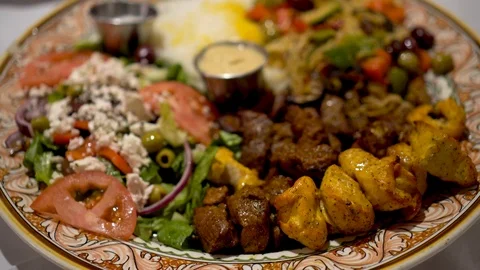 Closeup of middle eastern platter of kabobs, pasta, salad, rice, hummus with Stock Footage 88639678