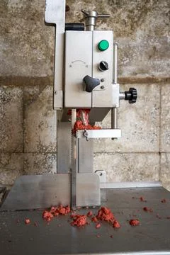 Closeup of minced meat on operating pan of industrial raw meat cutting machine Stockfoto's