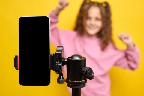 Closeup of mobile phone with empty display and little girl moving to music re Stock Photos