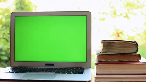 Closeup of modern laptop with green screen and lots old books on background. 스톡 동영상 114130367