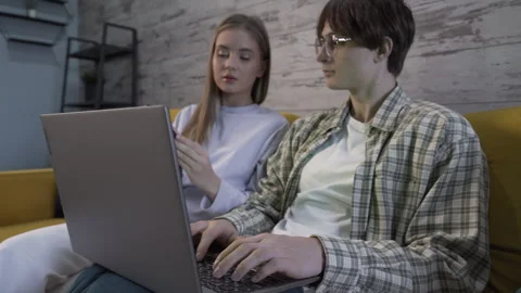 Closeup of a modern young couple on the couch and using gadgets and talking Stock Footage 259332190