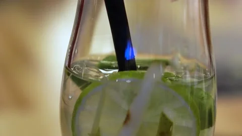Closeup of mojito with lime from glass which through a straw in a restaurant Stock Footage 153078614