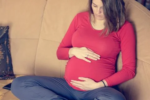 Closeup of mother hands caressing her pregnant belly. Stock Photos