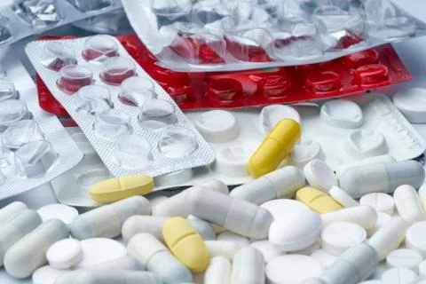 Closeup of multi-colored pills and empty packaging from drugs on a white back Stock Photos