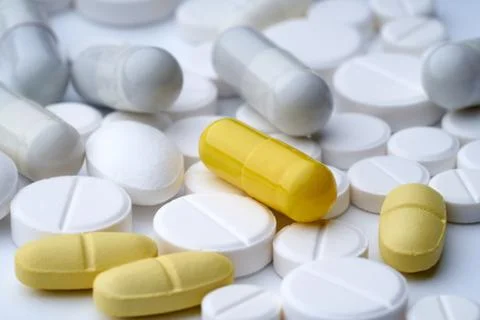 Closeup of multi-colored pills on a white background with texture. Stock Photos