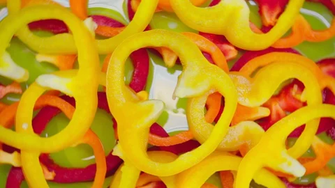 Closeup. Multi colored slices of bell pepper on a rotating background. top view 動画素材 128465460