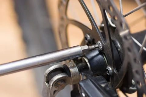 Closeup multi screwdriver working on mechanical parts next to wheel spokes Stock Photos