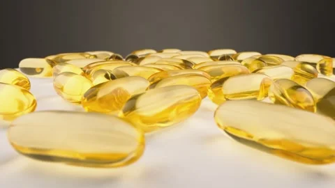 Closeup of multiple golden softgel capsules scattered on a white surface Stock Footage 341039780