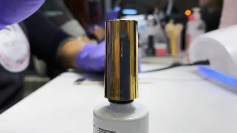 Closeup. Nails polish in bottle with a gold cap and brush. Woman in violet Video stock 119891712