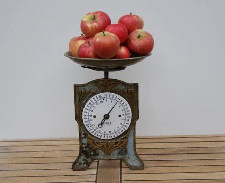 Closeup of a nostalgic kitchen scale with apples on the scales pan Stock Photos