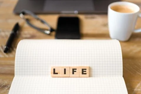 Closeup on notebook over wood table, focus on wooden blocks with letters Stock Photos