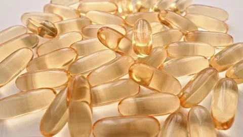 Closeup of numerous transparent softgel capsules scattered on a white surface Stock-Footage 341036351