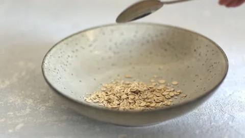 Closeup of oat flakes falling into the plate. Stock Footage 107815051