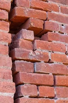 Closeup of an old brick wall with big crack and loose bricks. Stock Photos