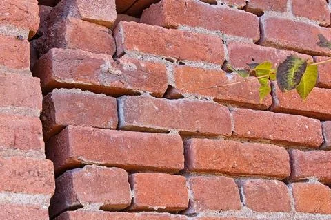Closeup of an old brick wall with big crack and loose bricks. Stock Photos