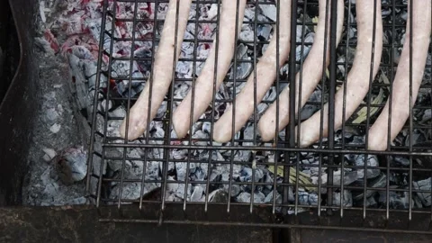 Closeup of old metal grill grid with raw Bratwurst sausages over charcoal Stock Footage 146747662