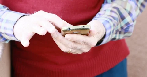 Closeup of old person's hands handling a smartphone Stock Footage 129721298