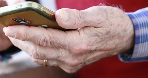 Closeup of old person's hands handling a smartphone Stock Footage 129722072