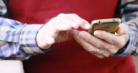 Closeup of old person's hands handling a smartphone Stock Footage 129722386