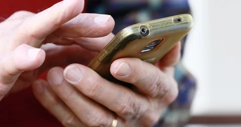 Closeup of old person's hands handling a smartphone Stock Footage 129722579