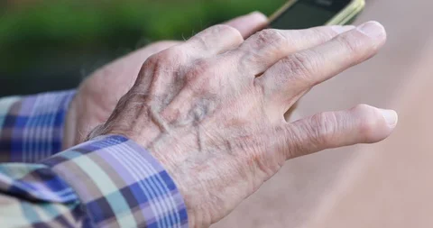 Closeup of old person's hands handling a smartphone Stock Footage 129722893