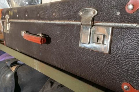 Closeup of old vintage suitcase on a shelf in abandoned garage. Stock Photos