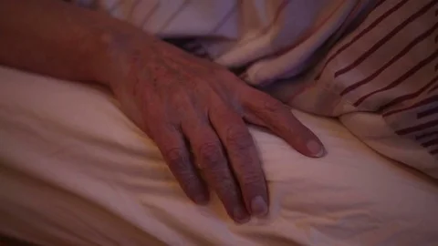 Closeup of old woman’s hand lying in bed and a male hand is caressing her Stock Footage 69901766