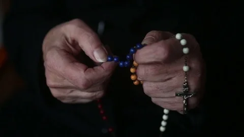 Closeup of old woman’s hands praying and holding a rosary Stock Footage 69771616
