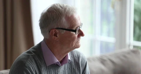Closeup older man sits on couch lost in sad thoughts Stock Footage 229619339