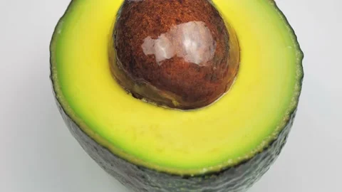 Closeup of one half cut avocado is rotating on the turntable. Isolated on white Stock Footage 219964969