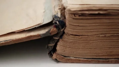 Closeup opening very old battered book turning over yellowed, dilapidated pages. Stock Footage 252698759