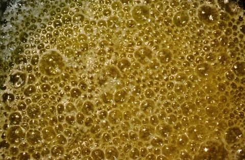 Closeup ov bubbles of golden melted butter while making home made ghee clarif Stock Photos