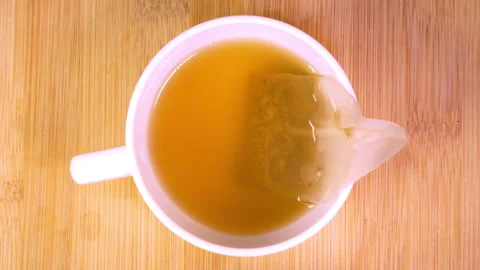 Closeup overhead transition from a stirred cup of coffee to infusing tea. Vidéo 301247528