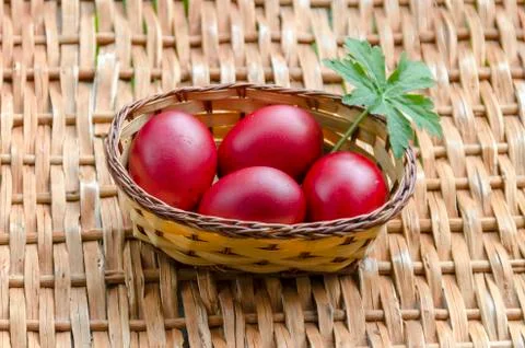 Closeup paint Easter red eggs in the basket on wicker table Stock Photos