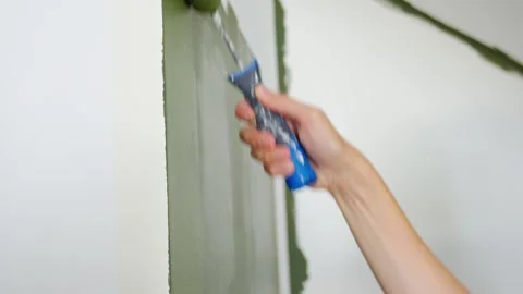 Closeup of paint roller applying green paint to white wall Stock Footage 345135467