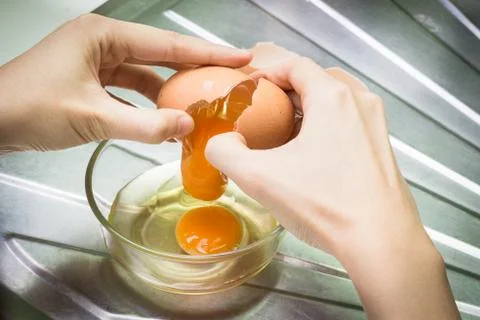 Closeup of a pair of hands cracking an egg into a glass bowl Stock Photos