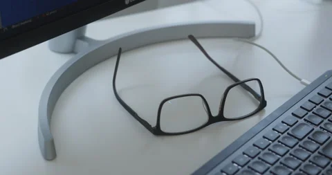Closeup Pan of Man Reaching for Reading Glasses on Work Desk Stock Footage 209595779