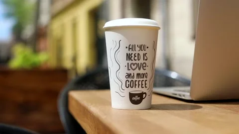 Closeup paper cup with coffee on table outdoor with modern laptop on blurred sun 스톡 동영상 132258054